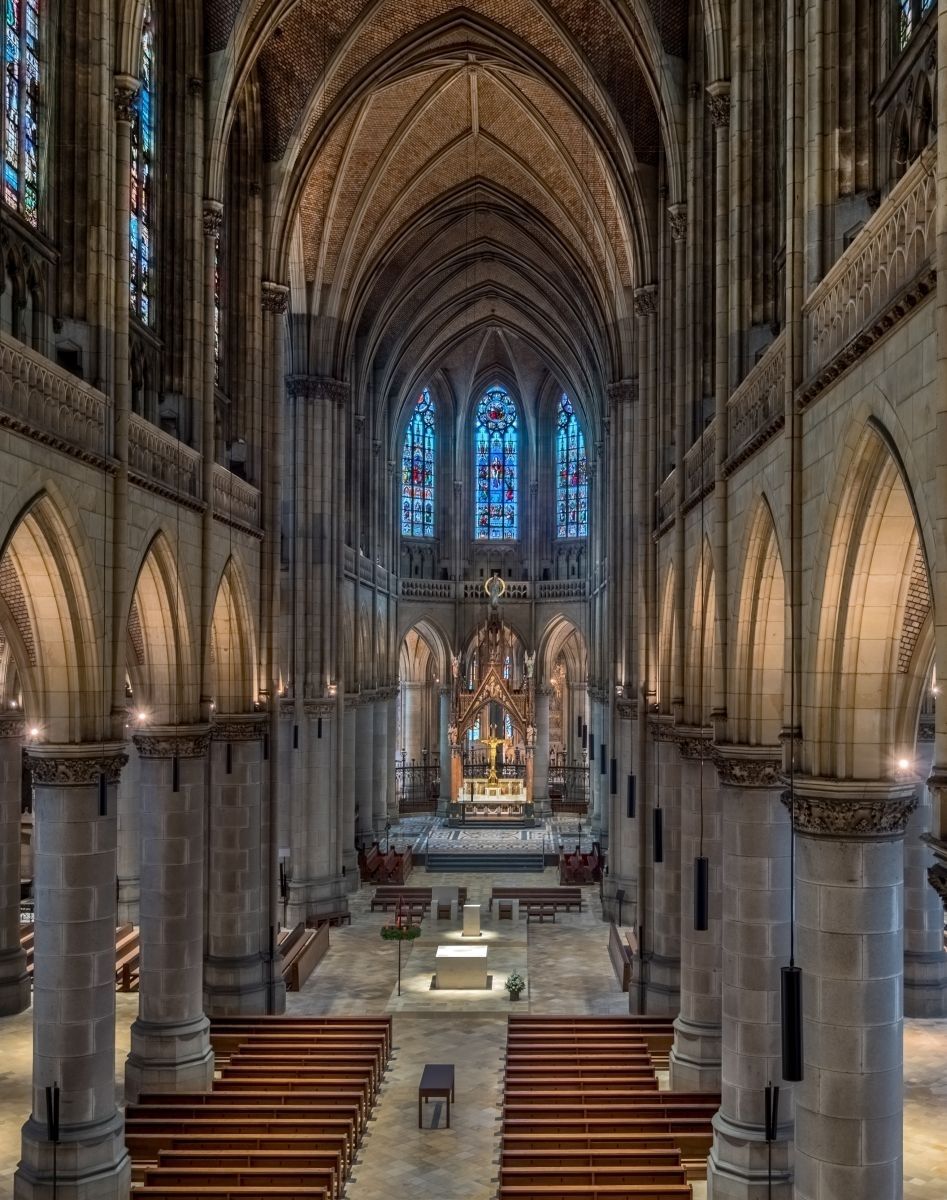 Innenraum einer gotischen Kathedrale mit gewölbten Decken und Buntglasfenstern.